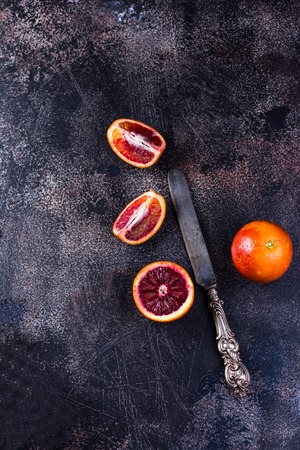 Whole and sliced sicilian oranges on a black slate background. High angle viewの写真素材