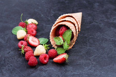 Waffle with fresh berries. Strawberries, raspberries and mint in waffle cones on a dark blue background.の写真素材