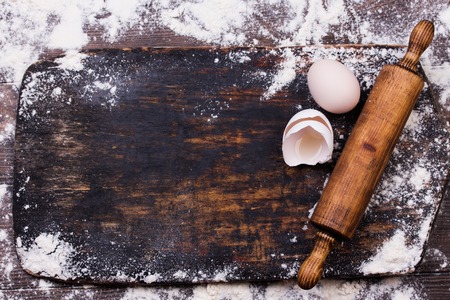 Baking background with free space for your text. Rolling pin, kitchen utensils, eggs and flour on black rustic bakery shovel . Copy space. Top viewの写真素材