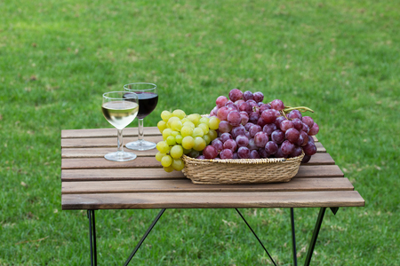 Tasty wine on wooden table on green lawn backgroundの写真素材