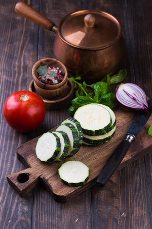 Zucchini with slices and onion on a wooden table.の写真素材