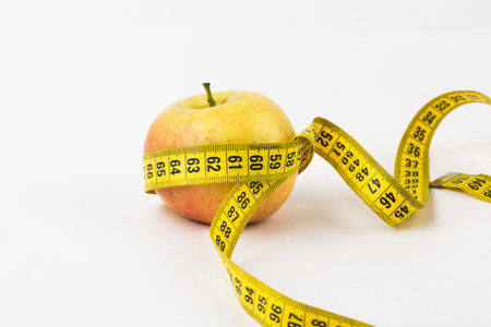 Flat lay composition with measuring tape and apple on white