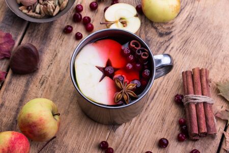 A mug of hot mulled wine, spices, cinnamon, star anise, apple and nuts on a wooden boardの写真素材