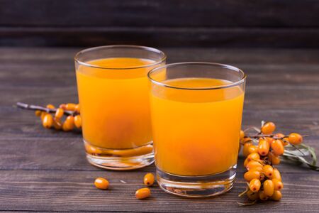 Glass of juice and branches of orange sea buckthornの写真素材