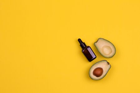 Fresh ripe avocado and avocado oil in little cosmetic bottle on a yellow background. Healthy lifestyle concept. Copy space. Place for your text.の写真素材
