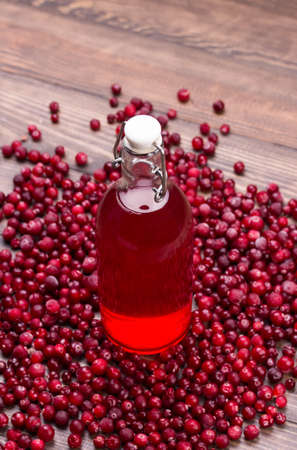 Organic cranberry juice in bottle with berries on wooden backgroundの写真素材