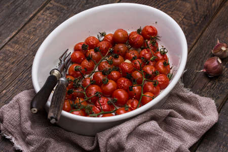Roasted cherry tomatoes with herbs in baking dish.の写真素材