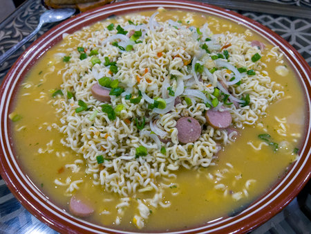 Noodle soup with sausage and onions in a bowl on the tableの写真素材