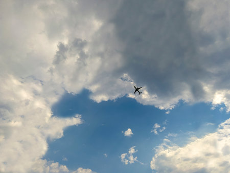 Airplane flying in the blue sky with white cloudsの写真素材