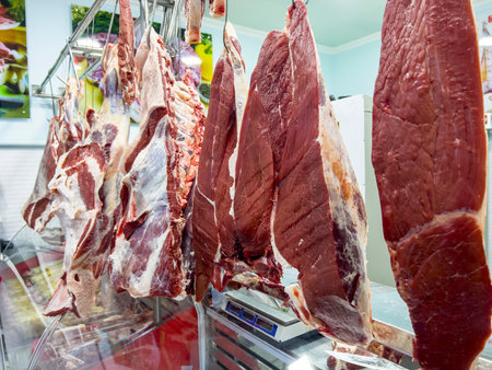 Slices of raw meat on display in a butcher shop.の写真素材
