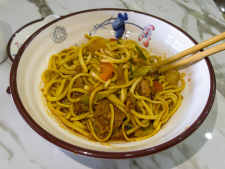 Noodles with pork and vegetables in a bowl on the table.の写真素材