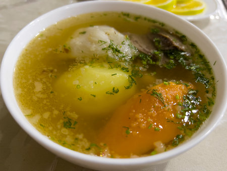 Chicken soup with egg and dill in a white bowl on the tableの写真素材