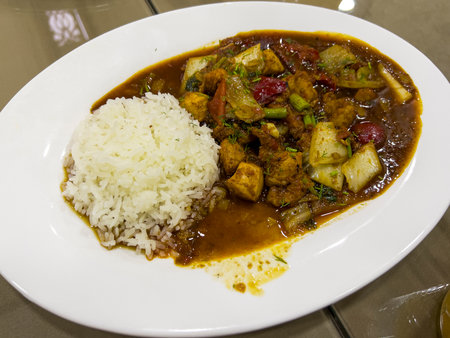 Rice with curry and chicken in a white plate on the tableの写真素材