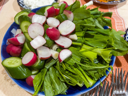 Radish, cucumber and spinach salad on a blue plate.の写真素材
