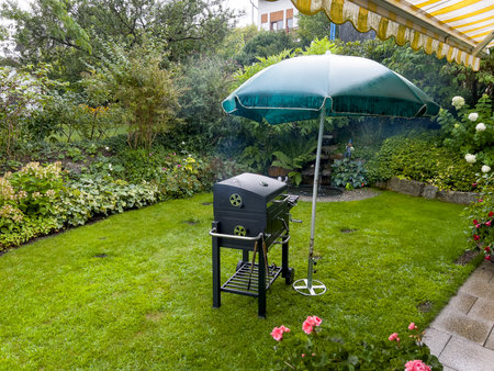 Outdoor barbecue grill with umbrella on the lawn in the garden.の写真素材