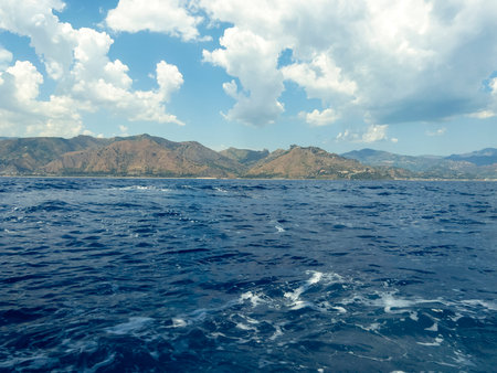 Hazy air, turquoise water and light blue sky with clouds.の写真素材
