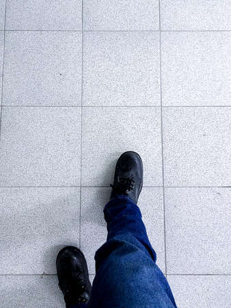 Seeing the feet of a man walking on the tiled floorの写真素材