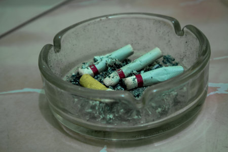 Glass ashtray filled with ash and cigarette butts