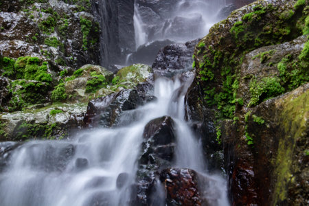 The water flows through the mossy rock, like a small waterfallの写真素材