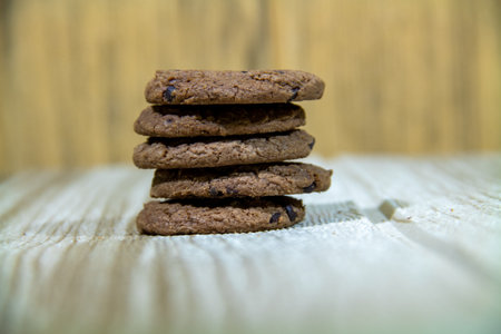 Pile of brown cookies against a wooden wall backgroundの写真素材