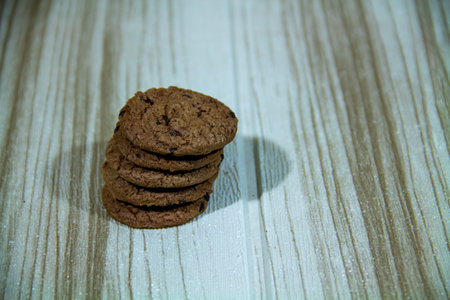Pile of brown cookies against a wooden wall backgroundの写真素材