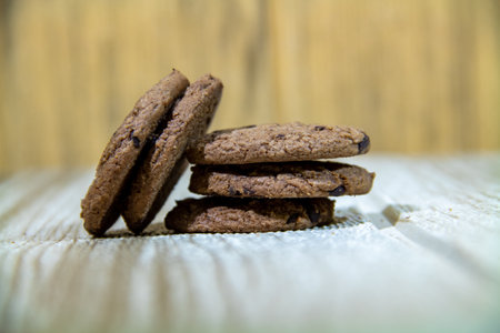 Pile of brown cookies against a wooden wall backgroundの写真素材