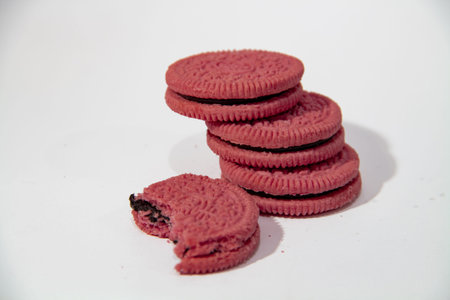 Half eaten pink biscuit on white background