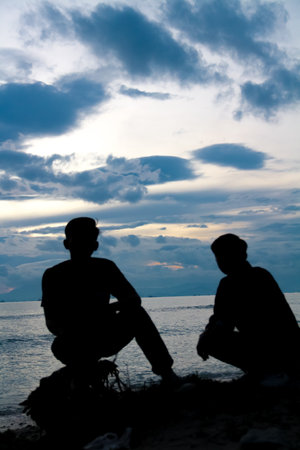 Silhouette of a man against the background of evening clouds on the beachの写真素材