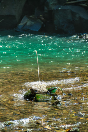 Small wooden stick on a stone in the middle of a mountain streamの写真素材