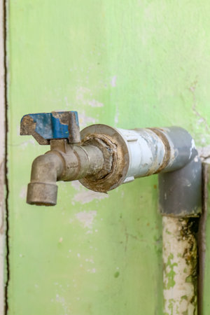 Old faucet on green wall background, closeup of photoの写真素材