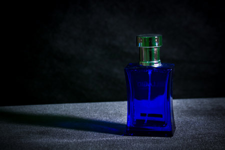 Square shaped blue glass perfume bottle on black backgroundの写真素材