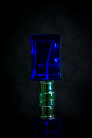 Square shaped blue glass perfume bottle on black backgroundの写真素材