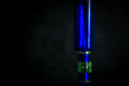 Blue glass perfume bottle on black backgroundの写真素材