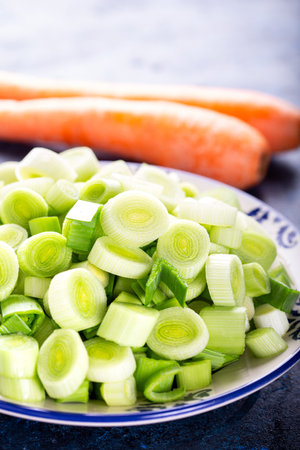 Fresh raw leek slice in a bowl with carrots. washed sliced ready-to-cook leeks.