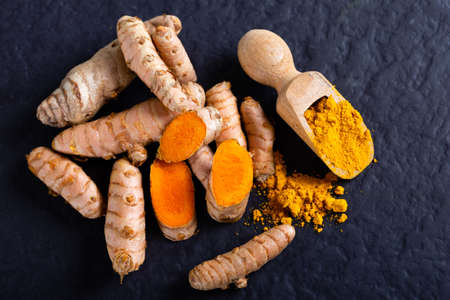Raw organic orange turmeric root and powder, curcuma longa on a grunge cooking table. Indian oriental low cholesterol spicesの写真素材