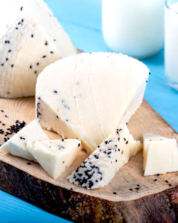 Cheese with black cumin seeds with bottle of milk on wooden background.の写真素材