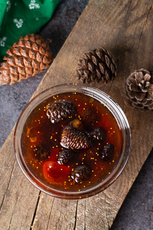 Young pine cones jam in glass bowl on wooden board. Delicious jam with the little pine cones.