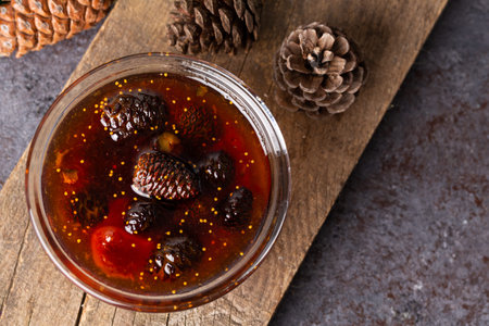 Young pine cones jam in glass bowl on wooden board. Delicious jam with the little pine cones.