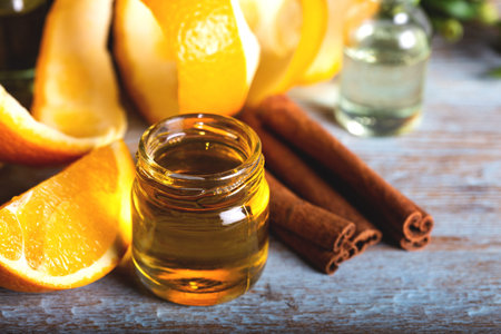 Bottle of orange essential oil with  orange slice, peel and leaf on wooden table.の写真素材