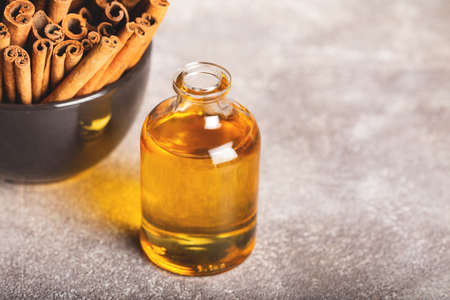 Essential cinnamon oil in a small bottle, ground cinnamon and cinnamon sticks on stone background.の写真素材