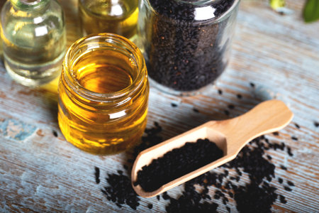Black cumin oil with seeds on wooden background