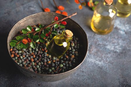 Small bottle of Pistacia terebinthus oil on the bowl of dried seeds on dark wooden background.の写真素材
