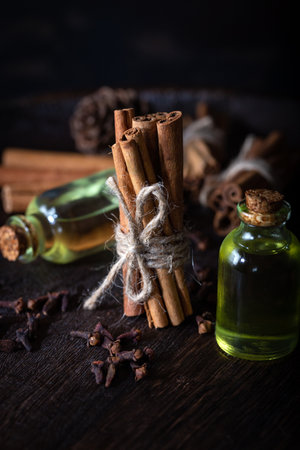 Selection of essential oils with  clove and cinnamon sticks on the wooden background.の写真素材