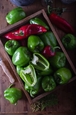Food preparation with fresh green bell pepper. Fresh green and red peppers in wooden box on the table.の写真素材