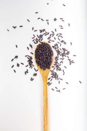 Black wild rice in a wooden spoon on white background.の写真素材