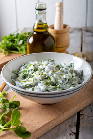 Purslane salad with fresh garlic yogurt and olive oil in white ceramic bowl on wooden background.の写真素材
