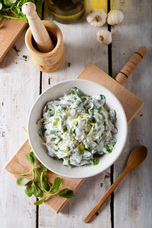 Purslane salad with fresh garlic yogurt and olive oil in white ceramic bowl on wooden background. Top view.の写真素材