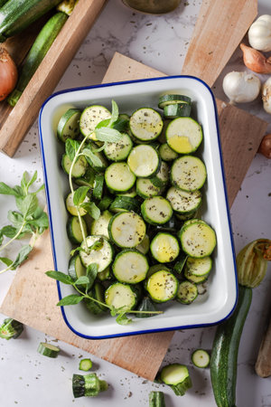 Sliced fresh green zucchinis in a ceramic baking dish. Top view.の写真素材