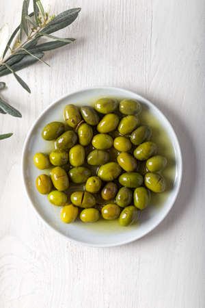 Green olives in a dish with herbs on a marble background.の写真素材