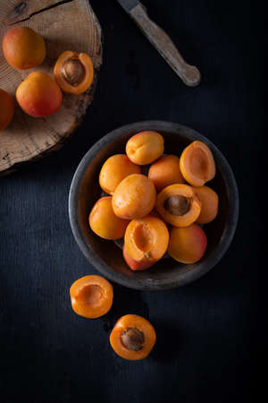 Fresh apricots in plate on dark wooden background. Top view.の写真素材